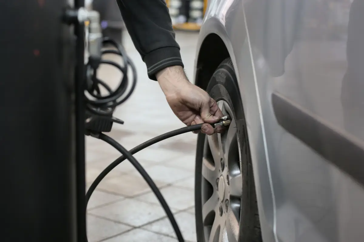 6 Ways To Save Fuel On Your Summer Road Trip. Checking tire pressure. Photo Courtesy of Pexels: https://www.pexels.com/photo/person-in-black-long-sleeve-shirt-holding-black-metal-bar-near-black-tire-3807450/